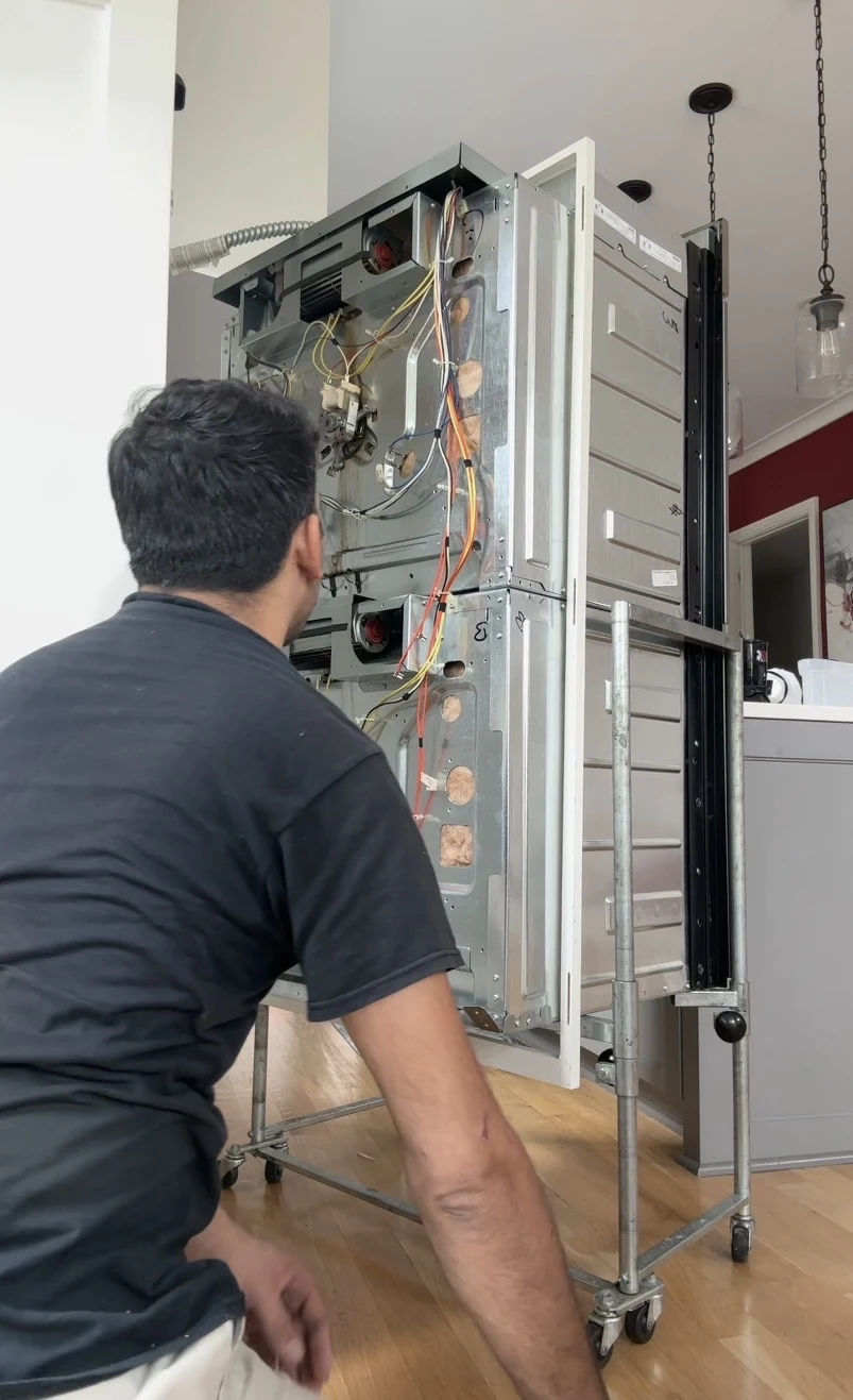 Technician servicing a built-in double wall oven in a customer’s home